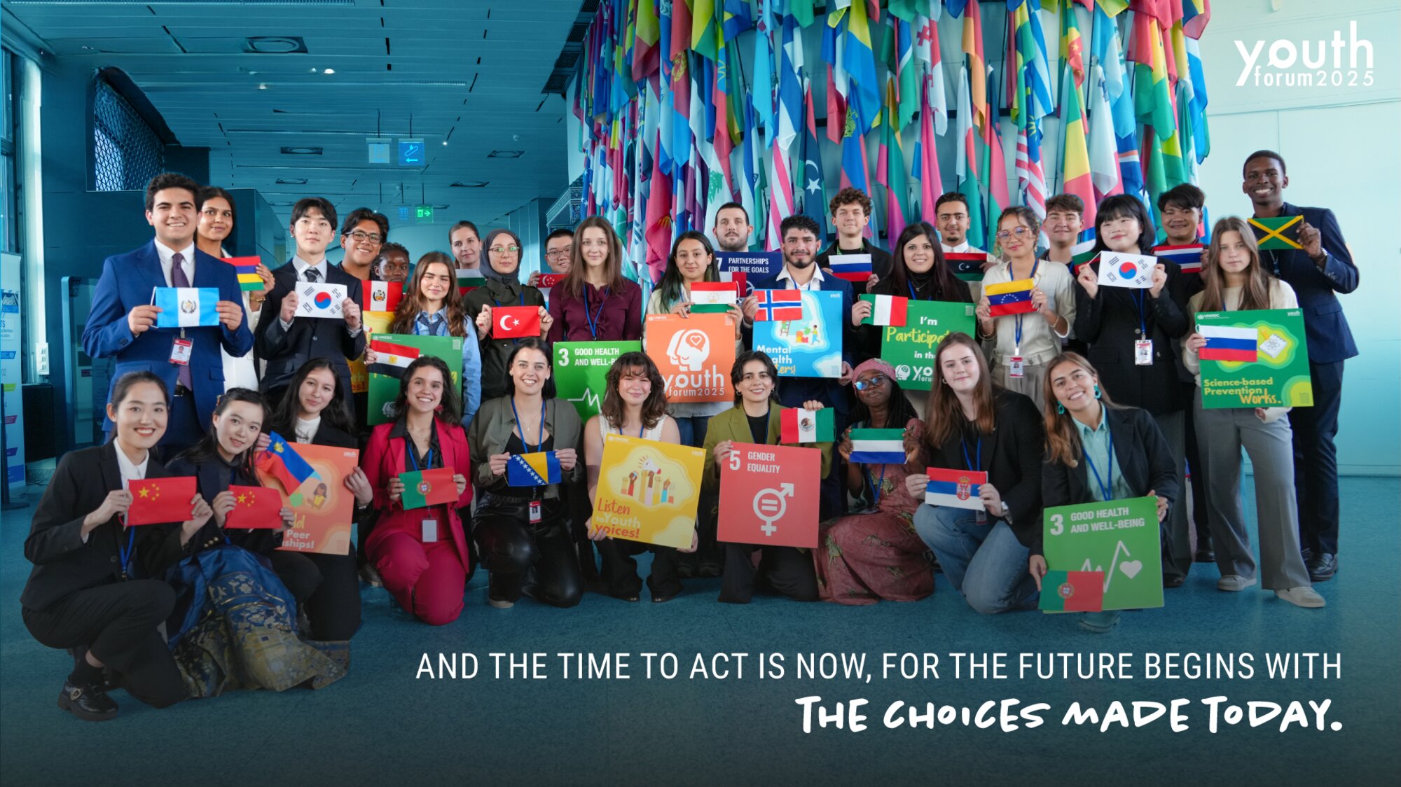 Young delegates from many countries holding flags and Sustainable Development Goal posters at the Youth Forum 2025